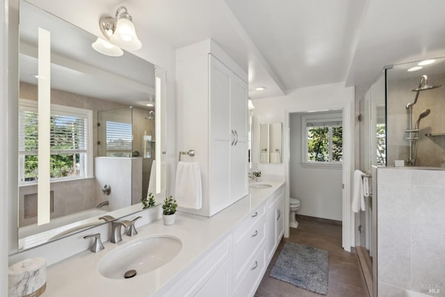 full bathroom featuring double vanity, an enclosed shower, a sink, and toilet