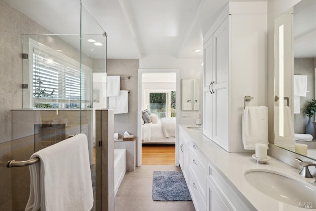 ensuite bathroom with double vanity, an enclosed shower, ensuite bathroom, a sink, and tile patterned flooring