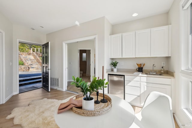 dining room with light wood finished floors, visible vents, and baseboards