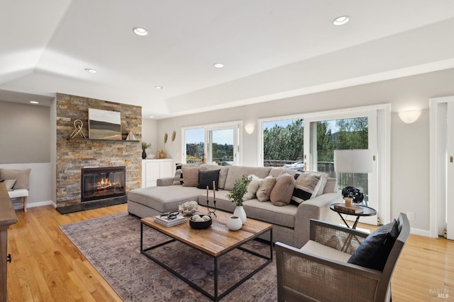 living room featuring recessed lighting, a stone fireplace, baseboards, and wood finished floors