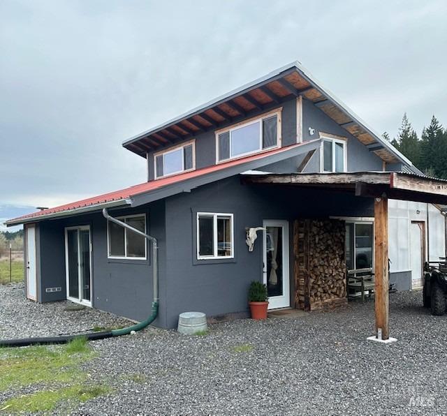 rear view of property with metal roof and stucco siding