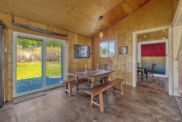 dining room with vaulted ceiling and wood walls