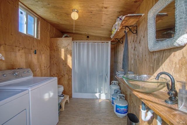 laundry room featuring laundry area, wood walls, wood ceiling, and washer and dryer