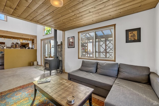 living room with carpet floors, wooden ceiling, and a wood stove