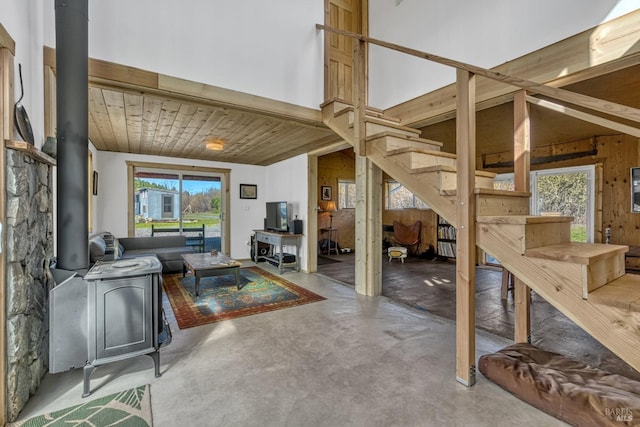 living room featuring wood ceiling, stairway, a wood stove, vaulted ceiling, and concrete floors