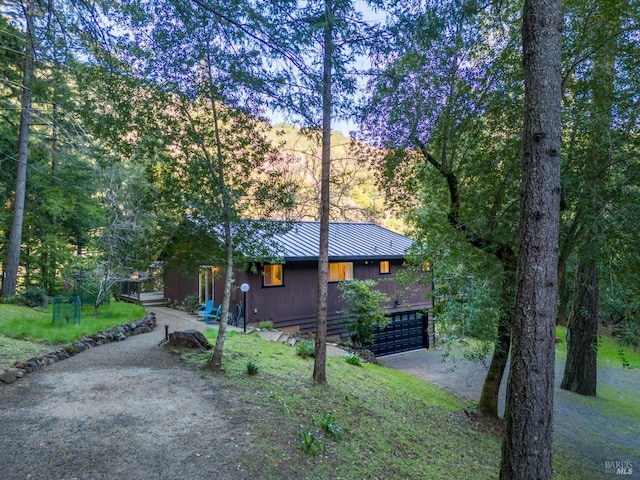 view of front of property featuring an attached garage, metal roof, a standing seam roof, and a front yard