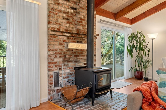 interior space with wooden ceiling, wood finished floors, baseboards, beam ceiling, and a wood stove