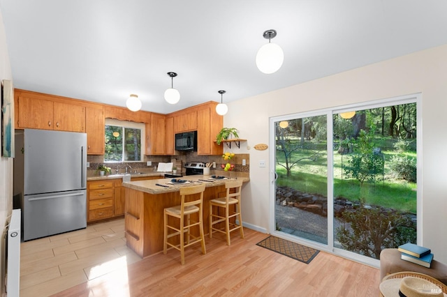 kitchen featuring decorative light fixtures, open shelves, stainless steel appliances, light countertops, and a peninsula