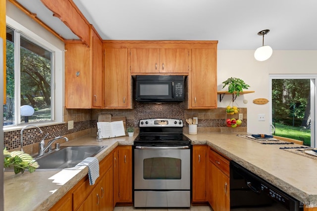 kitchen with brown cabinetry, decorative light fixtures, light countertops, black appliances, and a sink