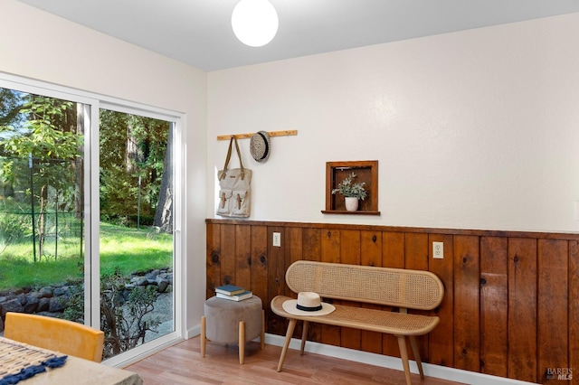 sitting room with light wood finished floors, wooden walls, and wainscoting