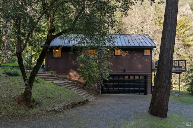 view of front of home with a garage, driveway, metal roof, a standing seam roof, and stairs