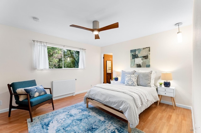 bedroom featuring ceiling fan, radiator heating unit, wood finished floors, and baseboards