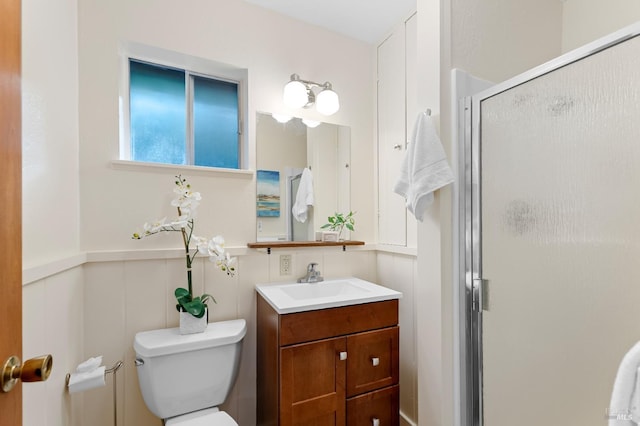 full bath featuring a wainscoted wall, toilet, a shower stall, and vanity