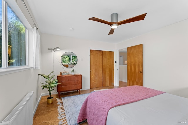 bedroom featuring radiator, ceiling fan, baseboards, and a closet