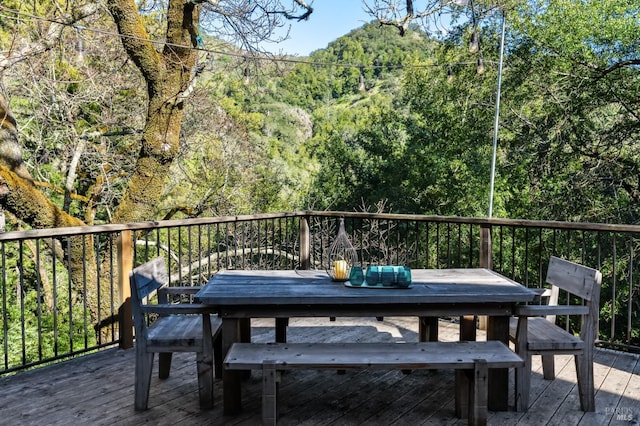 deck with outdoor dining area and a wooded view