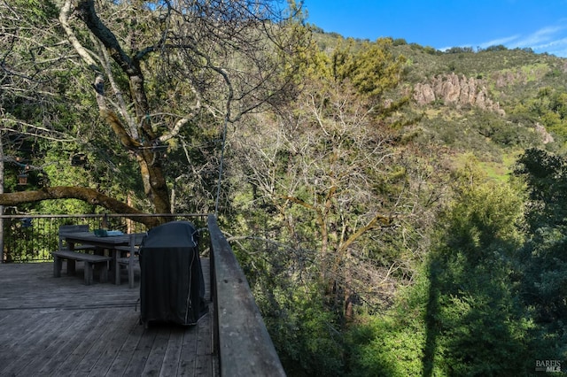 view of patio featuring a deck, outdoor dining area, and a wooded view