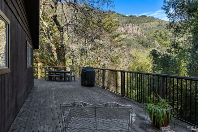 wooden deck with outdoor dining area, area for grilling, and a mountain view