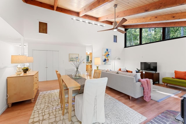 dining room with a high ceiling, light wood-style floors, a ceiling fan, wood ceiling, and beamed ceiling