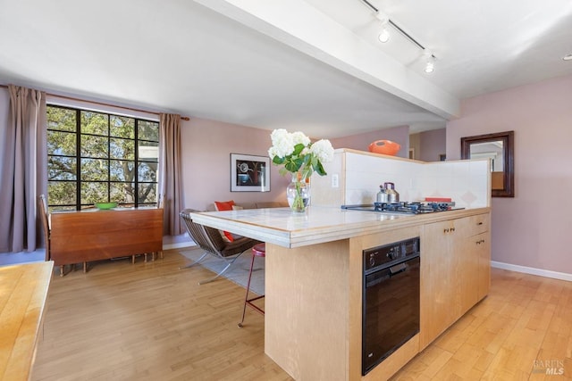 kitchen featuring a kitchen bar, a center island, stainless steel gas stovetop, and oven