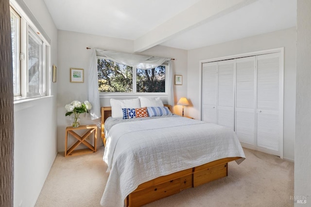 bedroom with a closet, beamed ceiling, and light colored carpet