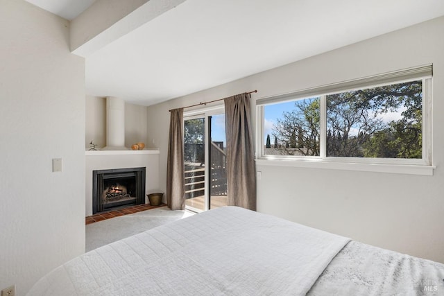 bedroom featuring light carpet, access to exterior, and a fireplace with flush hearth