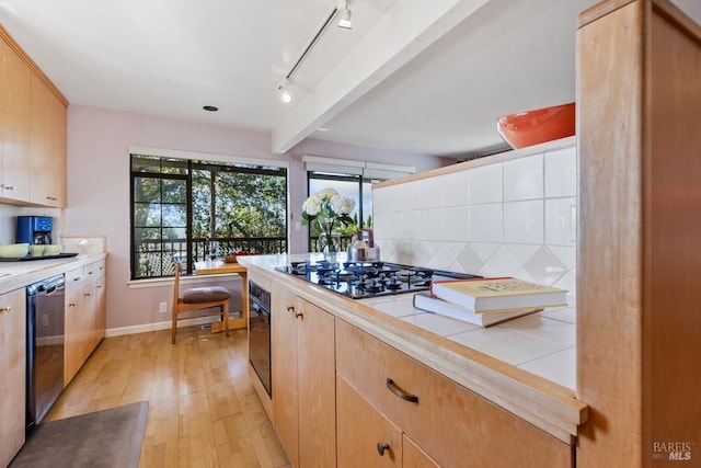 kitchen with tile counters, decorative backsplash, appliances with stainless steel finishes, light wood-type flooring, and beam ceiling