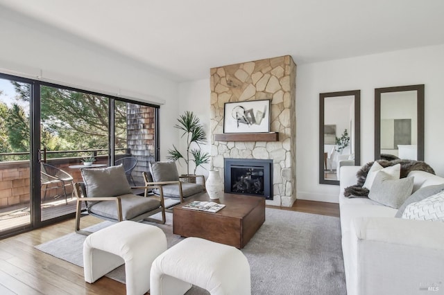 living room with wood finished floors and a stone fireplace