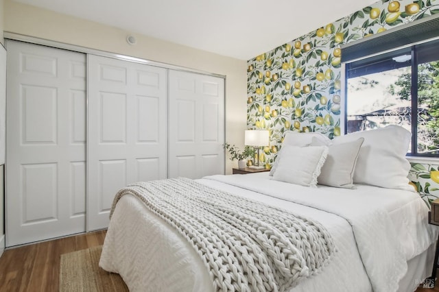 bedroom featuring wallpapered walls, dark wood finished floors, and a closet