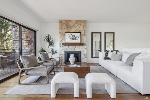 living area with a stone fireplace and wood finished floors