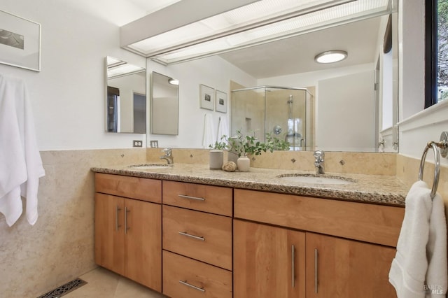 full bath with double vanity, tile patterned flooring, a sink, and a shower stall