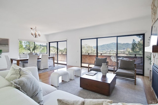 living area with a chandelier, wood finished floors, a mountain view, and baseboards