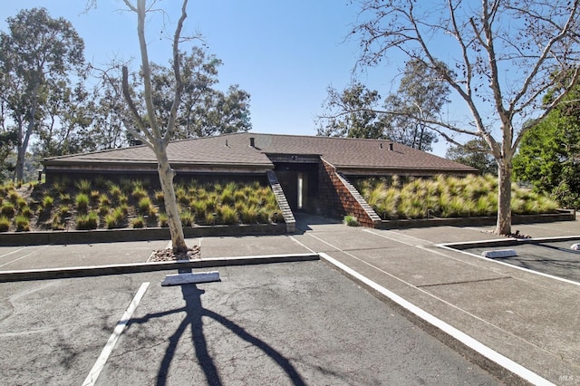 view of front of house featuring a shingled roof and uncovered parking