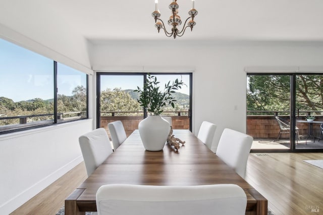 dining room with baseboards, light wood-style floors, and an inviting chandelier