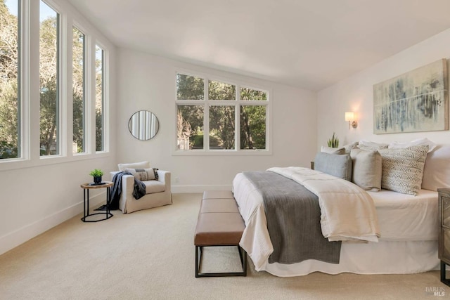 bedroom featuring lofted ceiling, light carpet, and baseboards