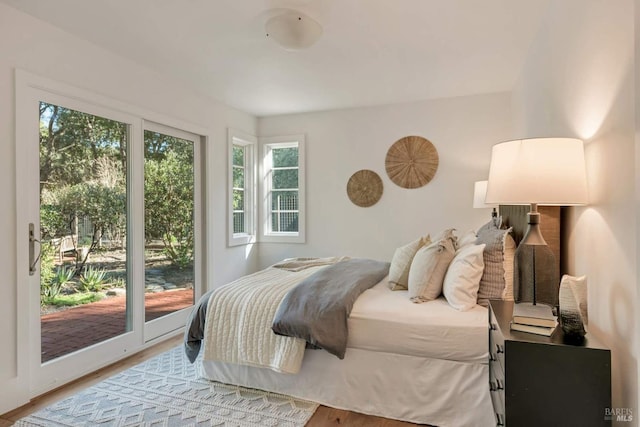 bedroom with access to outside and wood finished floors