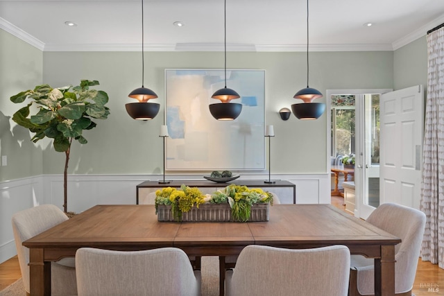 dining room featuring a wainscoted wall, ornamental molding, and light wood-style floors