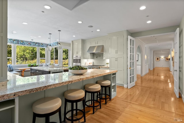 kitchen with a center island, white cabinets, hanging light fixtures, and under cabinet range hood