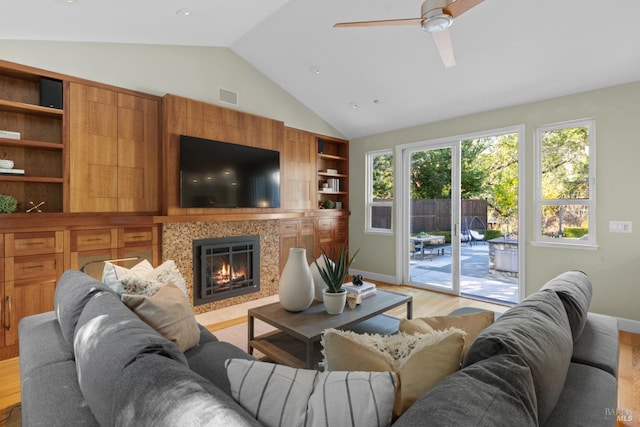 living area with light wood finished floors, visible vents, a tile fireplace, lofted ceiling, and built in shelves