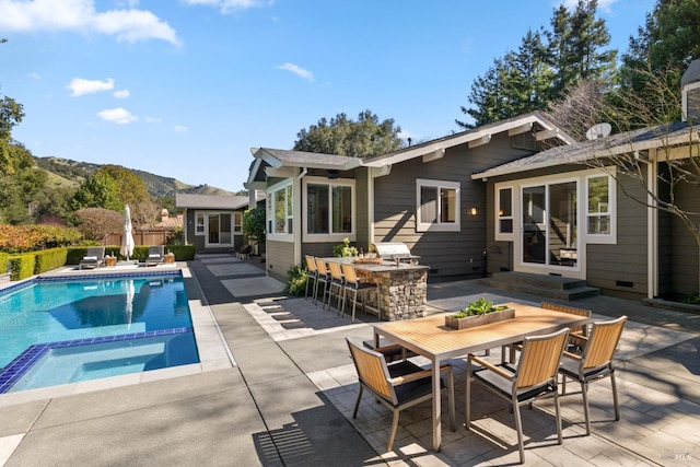 view of swimming pool with entry steps, a patio, outdoor dry bar, a mountain view, and outdoor dining space