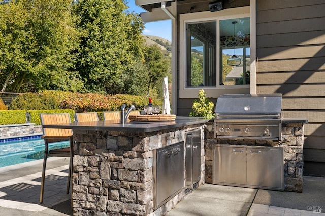 view of patio featuring an outdoor pool, an outdoor kitchen, grilling area, an outdoor bar, and a sink