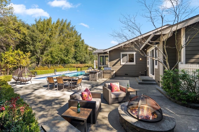 view of patio / terrace with an outdoor living space with a fire pit, fence, a fenced in pool, and area for grilling