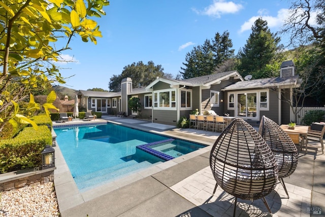 view of pool with outdoor dining space, a pool with connected hot tub, a patio area, and fence