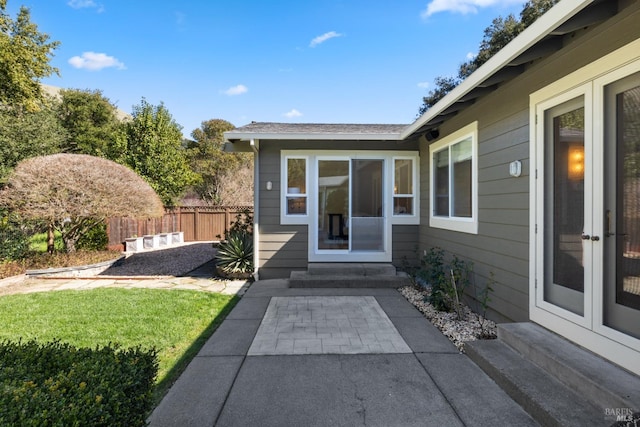 entrance to property with a patio area, fence, a lawn, and french doors