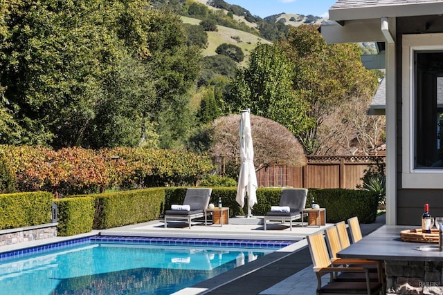 view of pool featuring a fire pit, a fenced in pool, fence, a patio area, and a mountain view