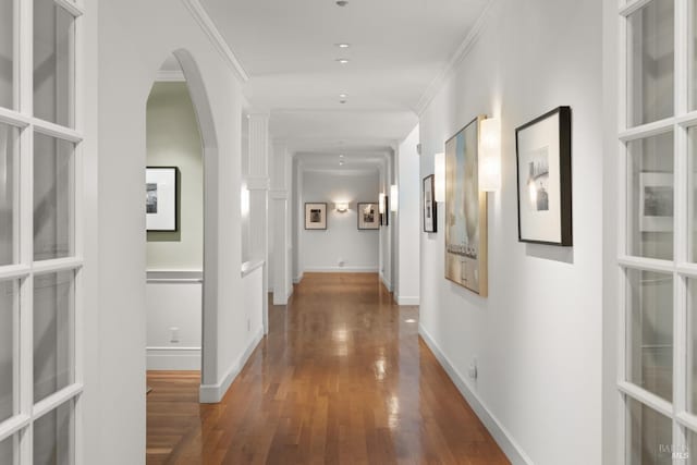 hall featuring ornamental molding, arched walkways, dark wood-style flooring, and baseboards