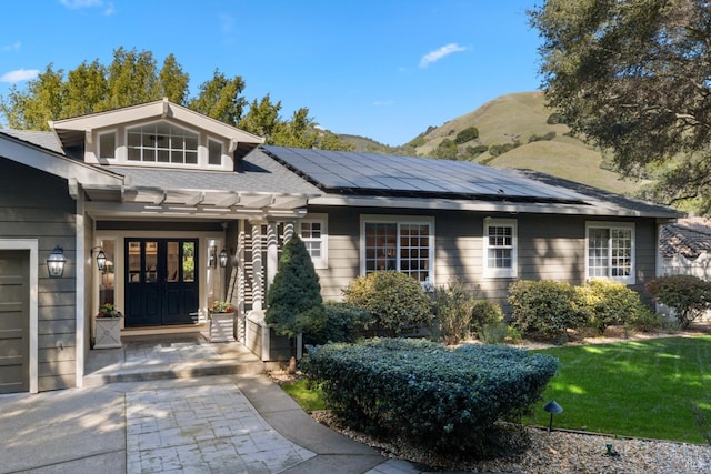 entrance to property with a garage, a mountain view, and roof mounted solar panels