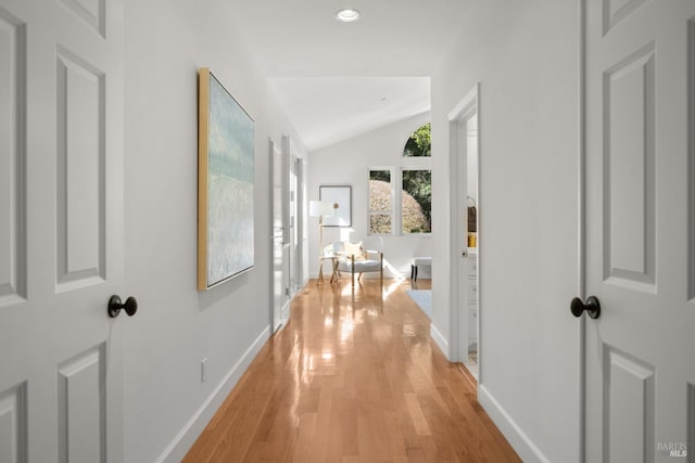 hall featuring light wood-style floors, recessed lighting, vaulted ceiling, and baseboards