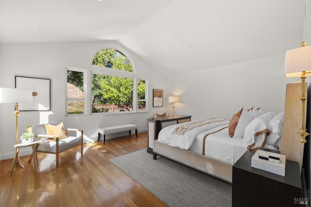 bedroom with lofted ceiling, light wood-style flooring, and baseboards