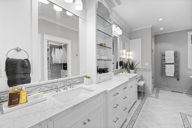 bathroom with recessed lighting, a sink, double vanity, a walk in closet, and crown molding