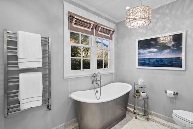 bathroom featuring crown molding, a freestanding bath, toilet, radiator heating unit, and baseboards